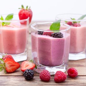 Drink smoothies four summer strawberry, blackberry, kiwi, raspberry on wooden table closeup.